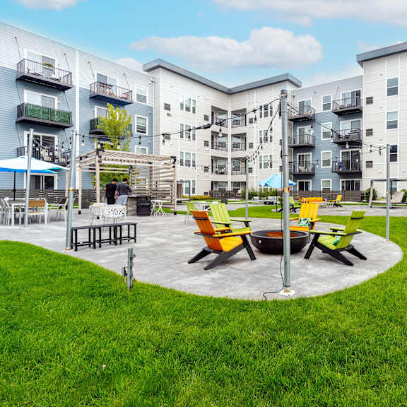 A round table with four chairs is in the middle of a grassy area.