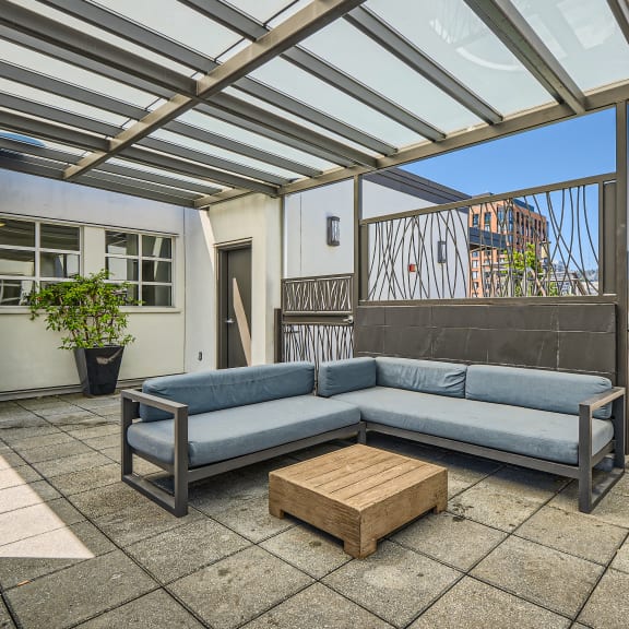 a patio with a gray couch and a wooden coffee table