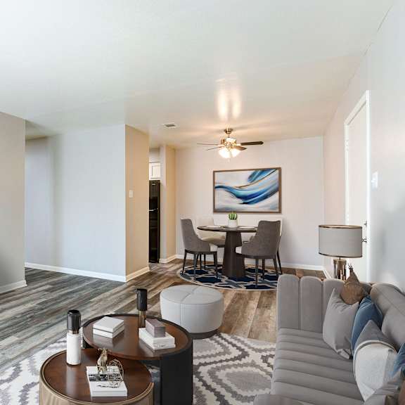 A modern living room with a grey sofa, a wooden coffee table, and a television on a white cabinet.