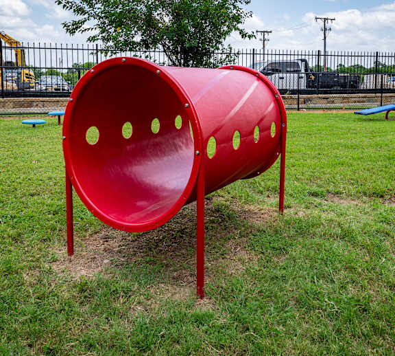 A red playground slide with four holes in the middle.