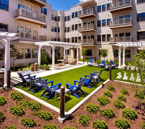 A white building with a balcony and a garden in front.