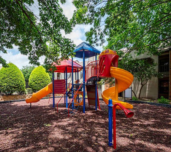 A playground with a yellow slide and a red and blue structure.