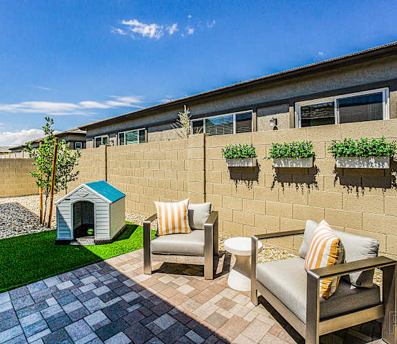 A patio with a couch, chair, and a dog house.
