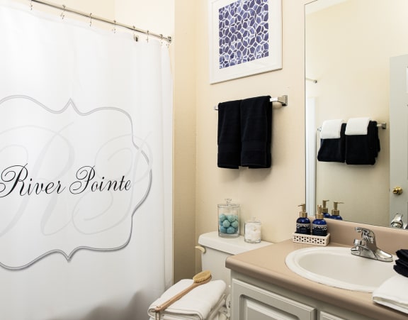 a white bathroom with a white shower curtain and navy towels