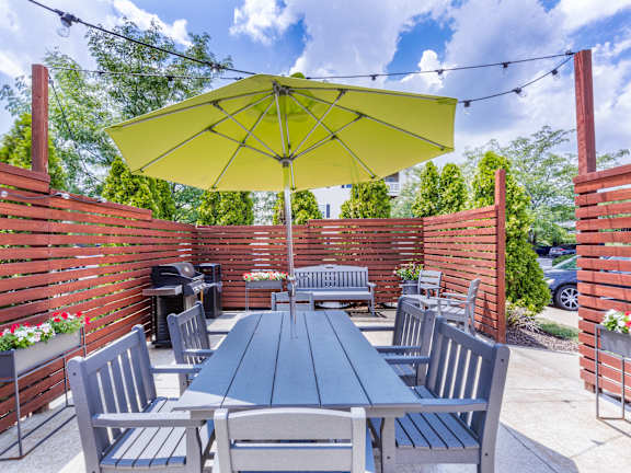 A yellow umbrella shades a table and chairs on a patio.