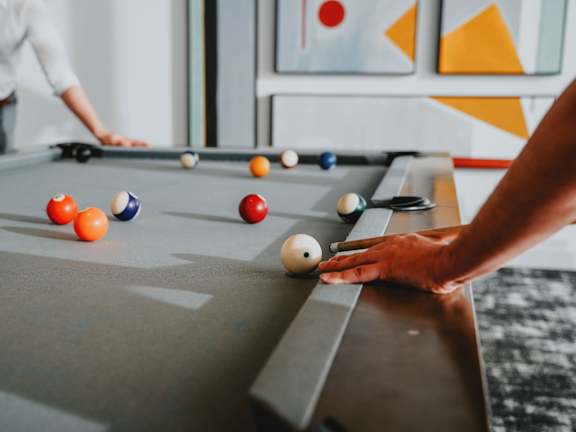 A man is playing pool with a white ball.