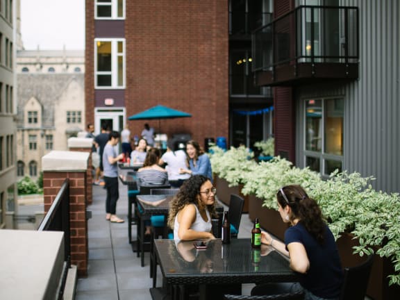 people sitting at tables on a patio in front of a brick building