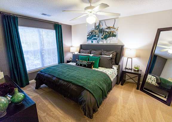 A bedroom with a bed, nightstand, and a mirror.