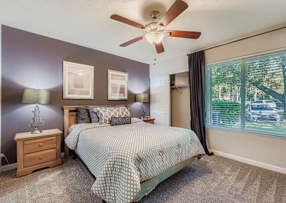A bedroom with a bed, dresser, and ceiling fan.