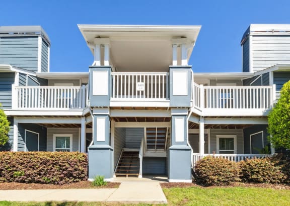 an apartment building with blue pillars and a white staircase