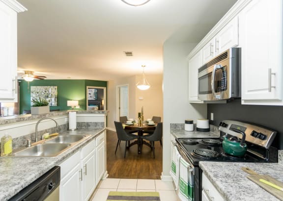 a kitchen with white cabinets and stainless steel appliances and a dining room with a table
