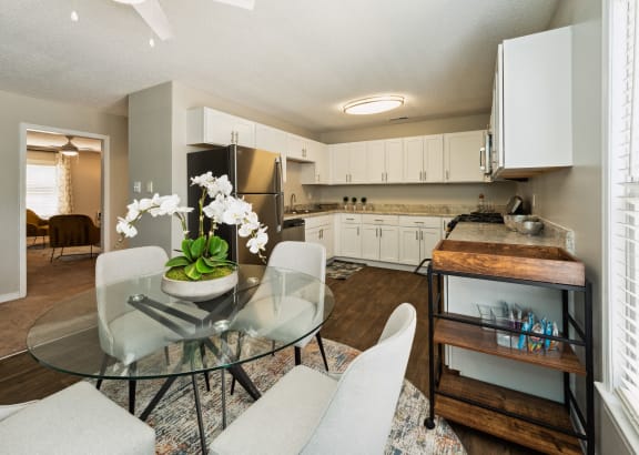 a kitchen and dining room with white cabinets and a glass table