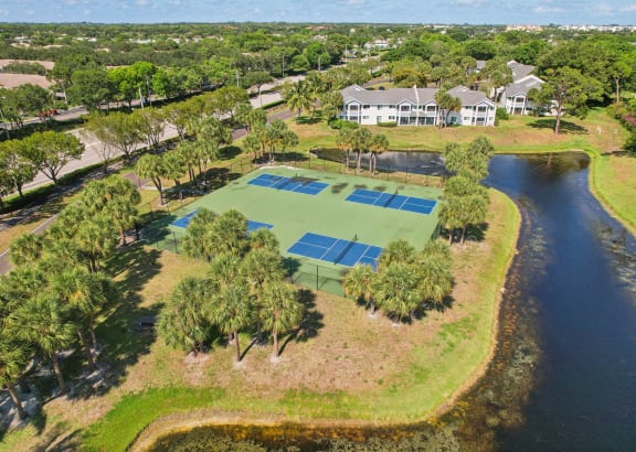 a tennis court with a house on the side of a lake