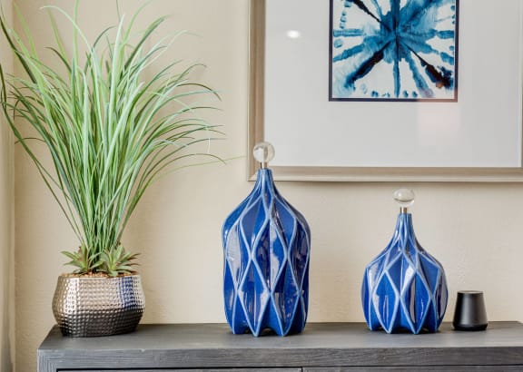 three blue vases sitting on a table with a plant