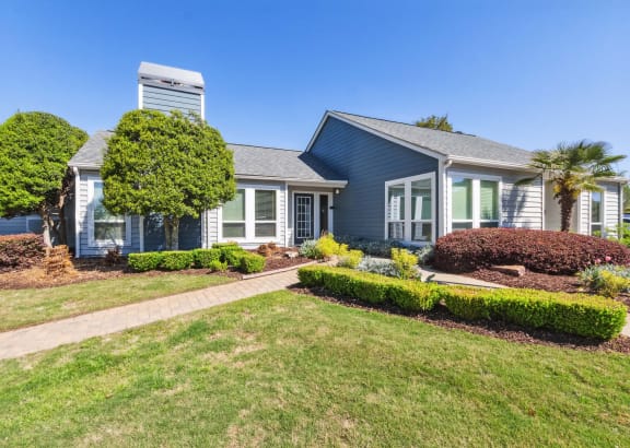 a blue house with a lawn and a sidewalk in front of it