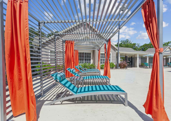 a row of lounge chairs with orange curtains in front of a building