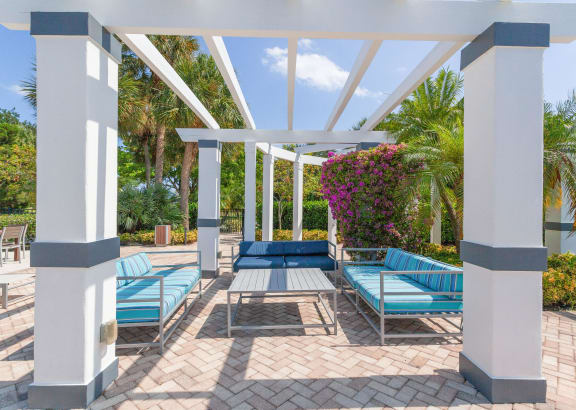 a patio with blue couches and chairs under a white roof