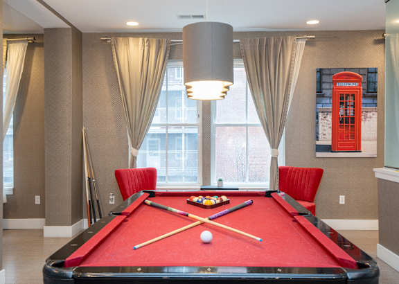 a red pool table in a room with two red chairs