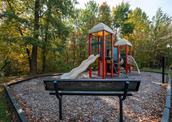 a park bench in front of a playground at SomerHill Farms Apartments in Gainesville, VA