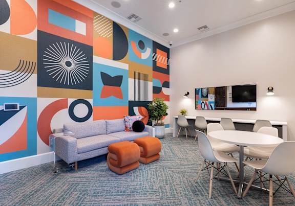 a living room with a couch and chairs and a wall with a mural