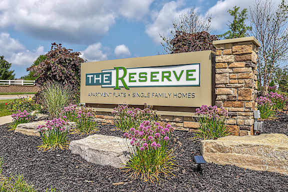 A sign for "The Reserve Apartments & Single Family Homes" is displayed in front of a landscaped area.