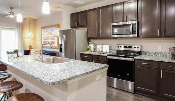 A kitchen with dark brown cabinets and a granite countertop.