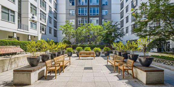 an outdoor patio with benches and potted plants in front of an apartment building