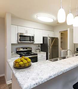 full kitchen with granite counter top and stainless steel appliances at the district flats apartments