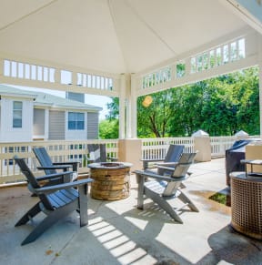 a covered patio with chairs and tables and a house in the background
