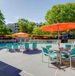 a patio with a pool and tables with umbrellas