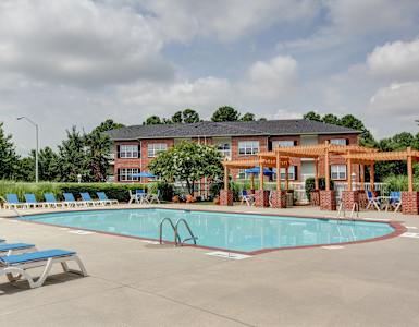 A pool with chairs and a building in the background.