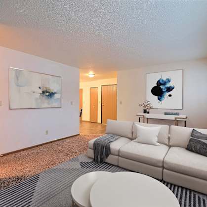 a living room with a white couch and a gray and white rug. Fargo, ND Kennedy Apartments