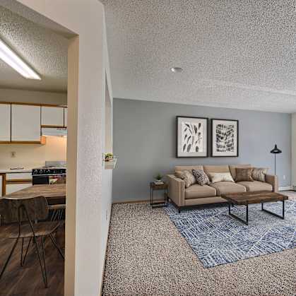 an open living room and kitchen with a couch and a table. Fargo, ND Park Place Apartments