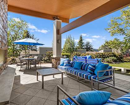 a covered patio with blue couches and chairs and a table with an umbrella