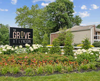 the grove apartments sign in front of flowers and plants