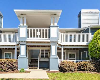 an apartment building with blue pillars and a white staircase at Palmetto Place Apartments, Taylors, South Carolina