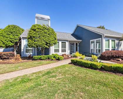 a blue house with a lawn and a sidewalk in front of it
