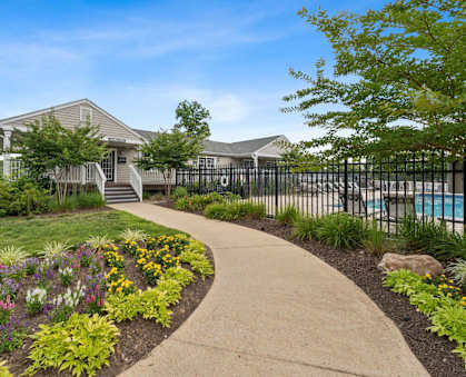 a sidewalk in front of a house with a pool