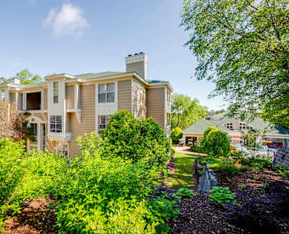 the view of the house from the yard with trees and bushes