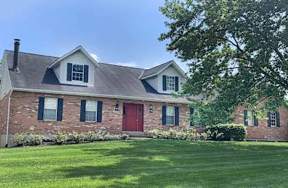 a brick house with a red door and a lawn  at The Villas at Kingswood, West Chester, 45069