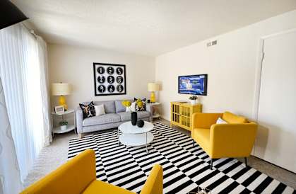 a living room with yellow furniture and a black and white rug