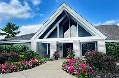 the front entrance of a white house with flowers and bushes at Deercross Apartments, Cincinnati, Ohio