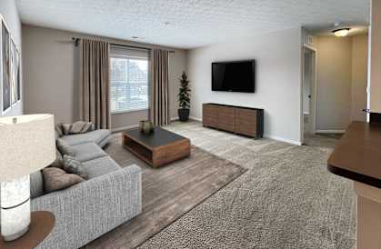 A living room with a grey couch, a wooden coffee table, and a flat screen TV mounted on the wall.