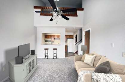 A living room with a television, a couch, and a ceiling fan.