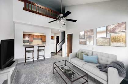 A living room with a white couch, a television, and a bar area.