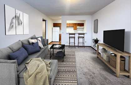 A living room with a grey couch and a television on a wooden stand.