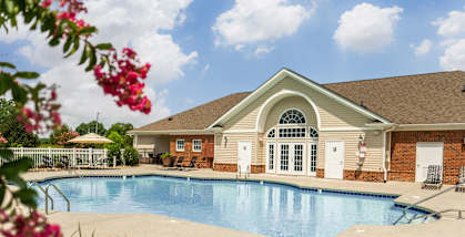 A pool in front of a house with a brown roof.