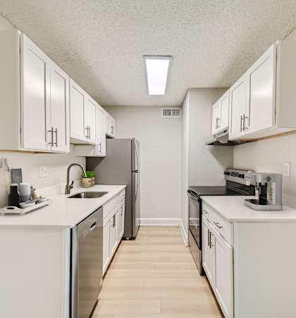 Bright galley-style kitchen with white cabinetry and updated appliances in Aurora, Colorado.