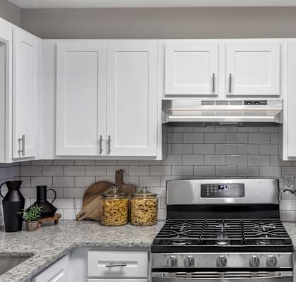 a white kitchen with stainless steel appliances and white cabinets at The Austin Apartment Homes, New Jersey