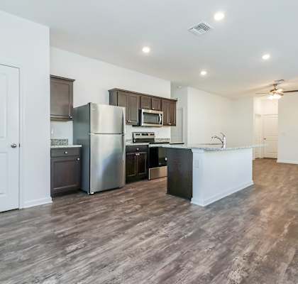 A kitchen with a refrigerator, microwave, and oven.